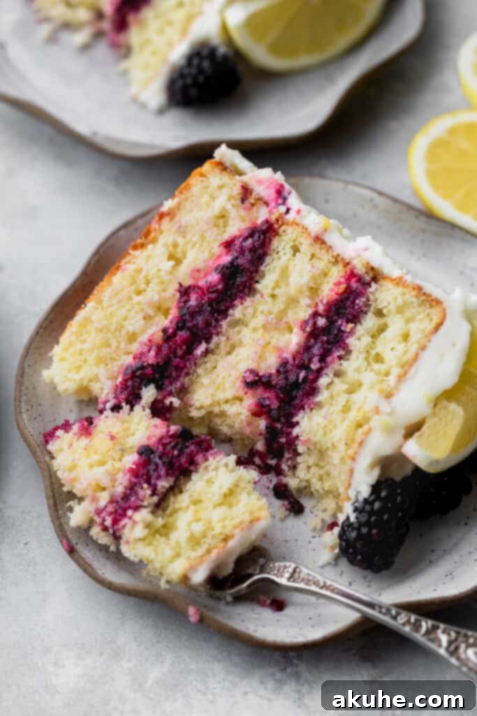 Zesty Lemon Blackberry Delight 2 A fork taking a slice out of a beautifully layered Lemon Blackberry Cake, showcasing its vibrant layers and frosting.