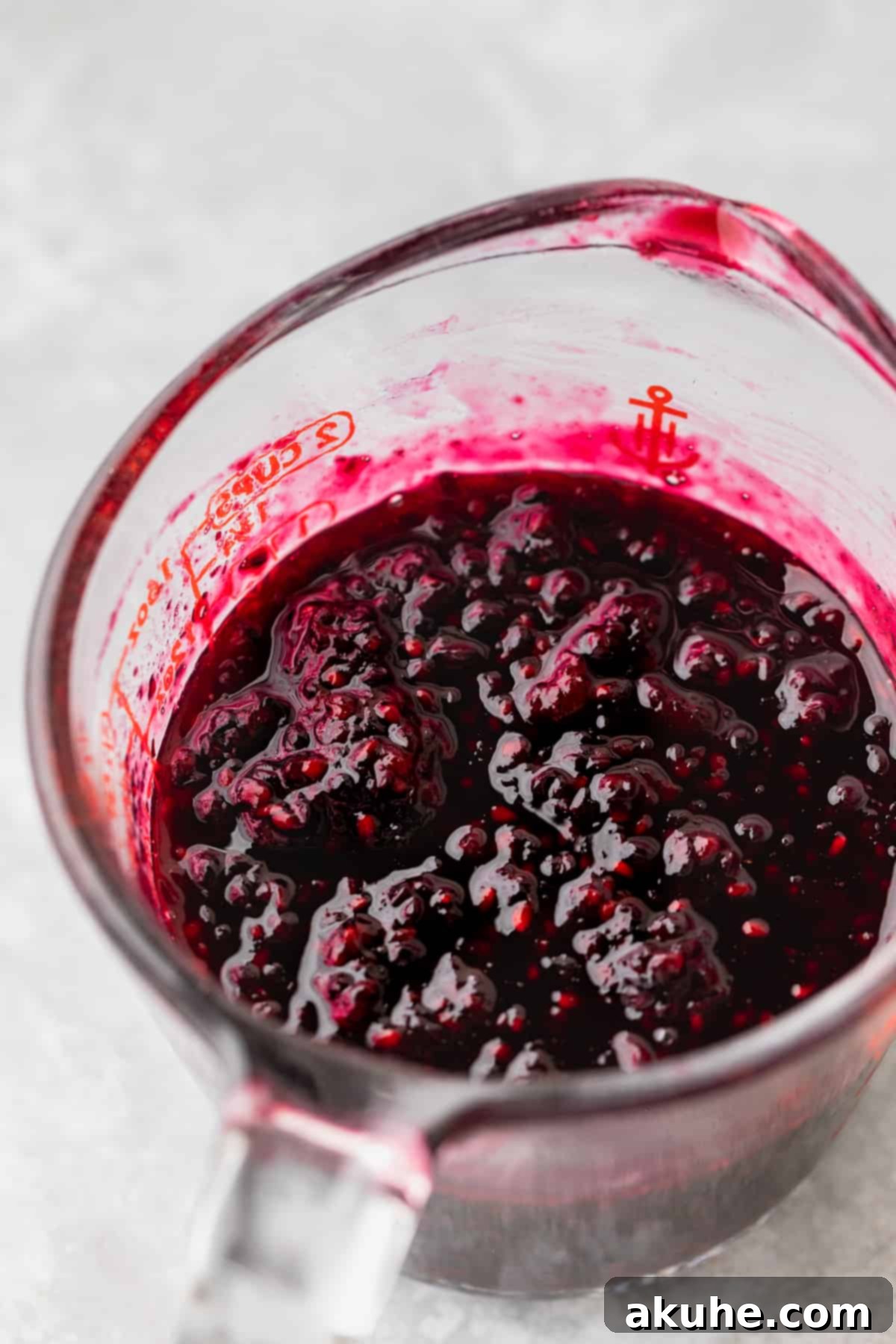 Zesty Lemon Blackberry Delight 8 Homemade blackberry jam poured into a glass measuring cup, showing its thick texture.