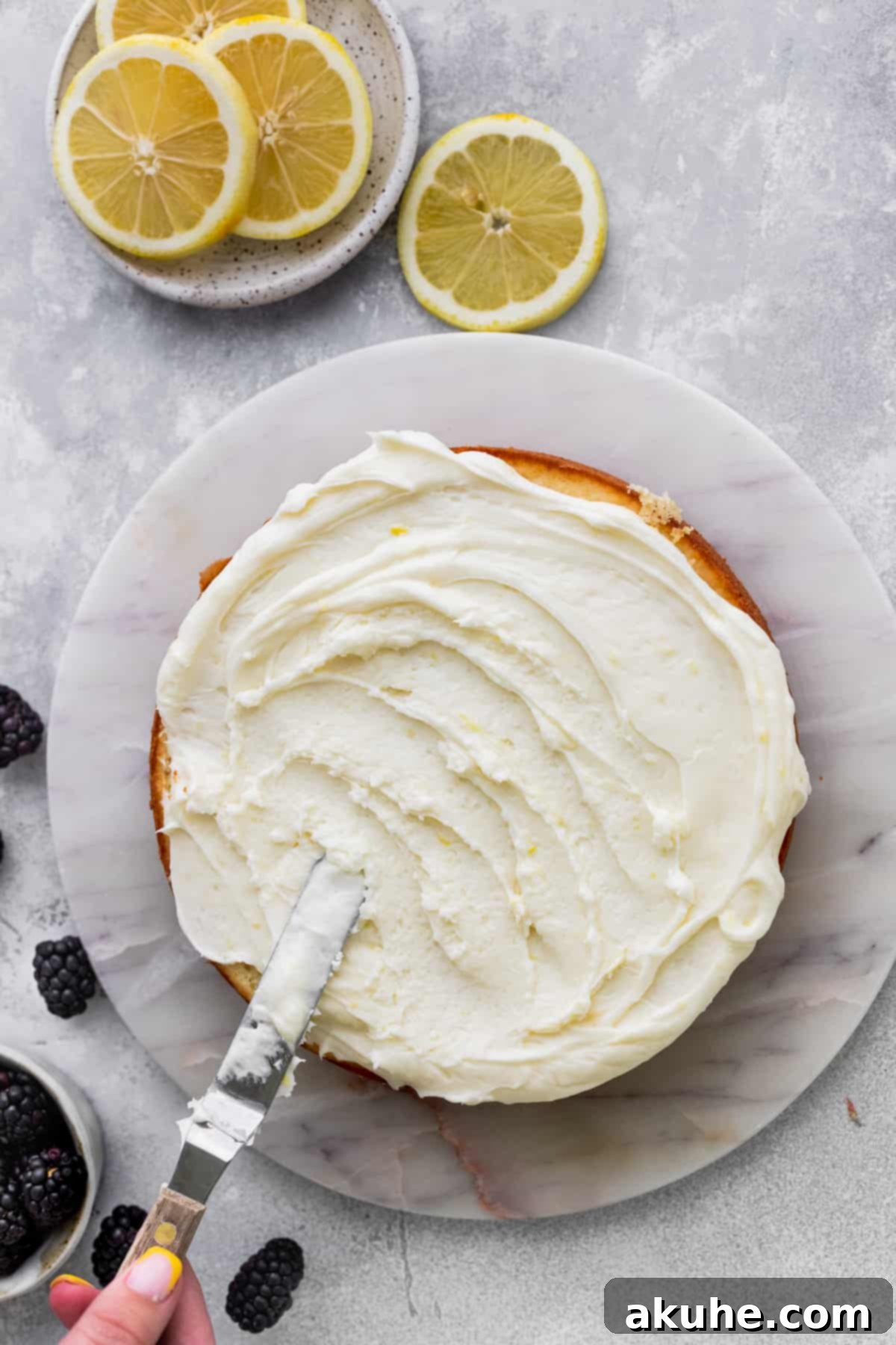 Zesty Lemon Blackberry Delight 10 Spreading smooth lemon cream cheese frosting on top of a cake layer.