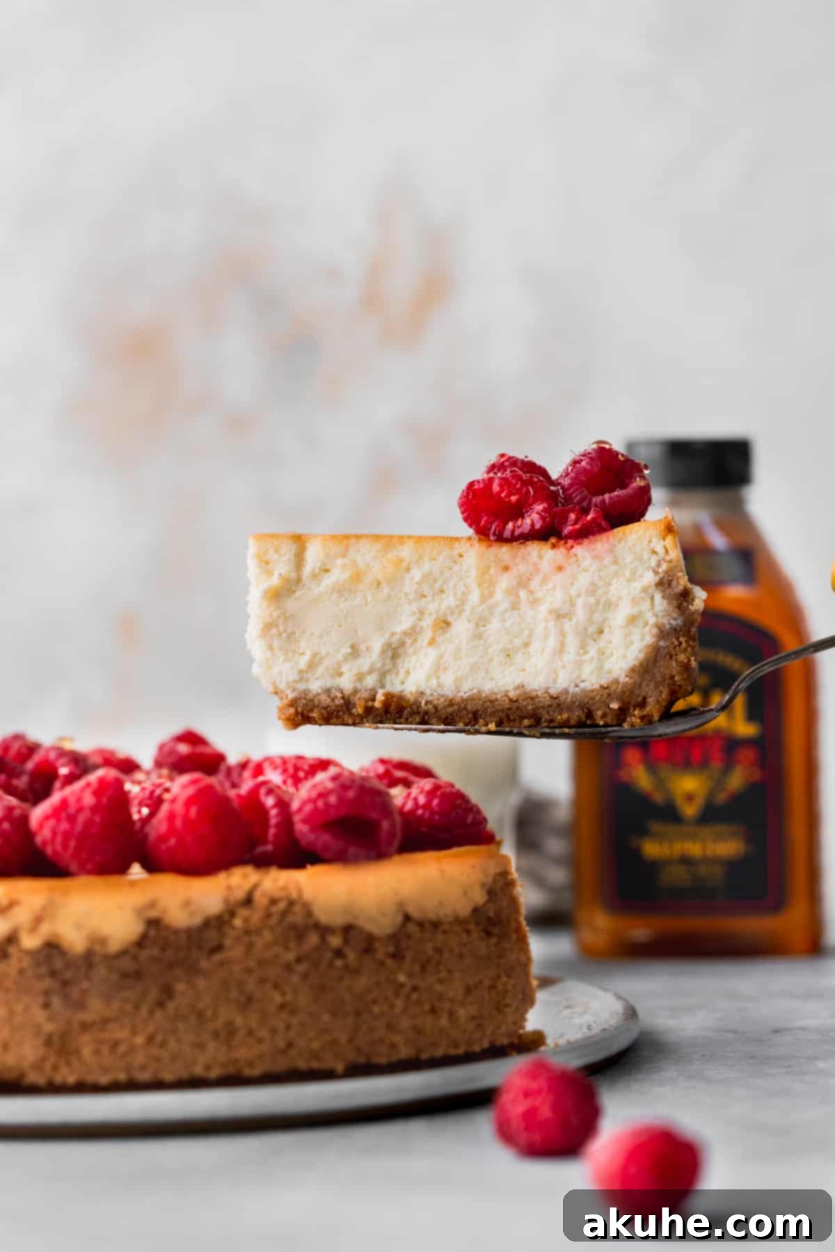 Pulling a slice out of the creamy honey cheesecake, revealing its rich texture and graham cracker crust.