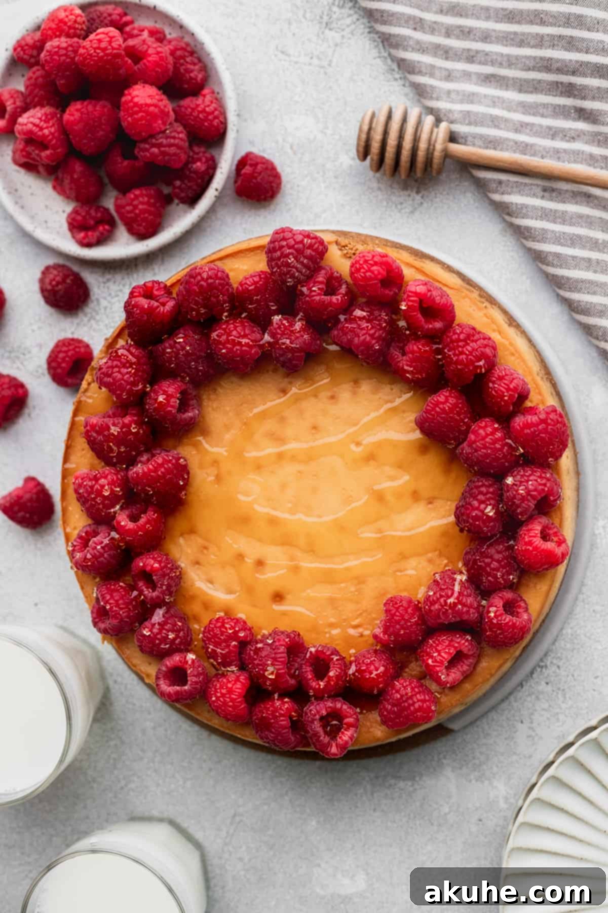 Honey cheesecake adorned with fresh raspberries and a delicate honey drizzle on top.