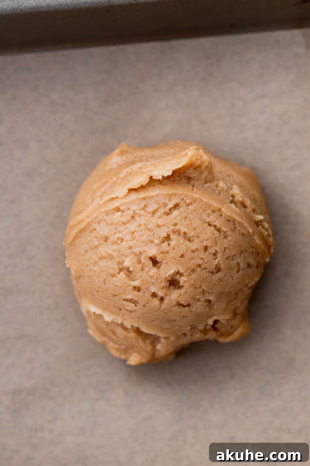 Snickerdoodle Peanut Butter Bliss 6 A scoop of peanut butter cookie dough on parchment paper on a cookie sheet.