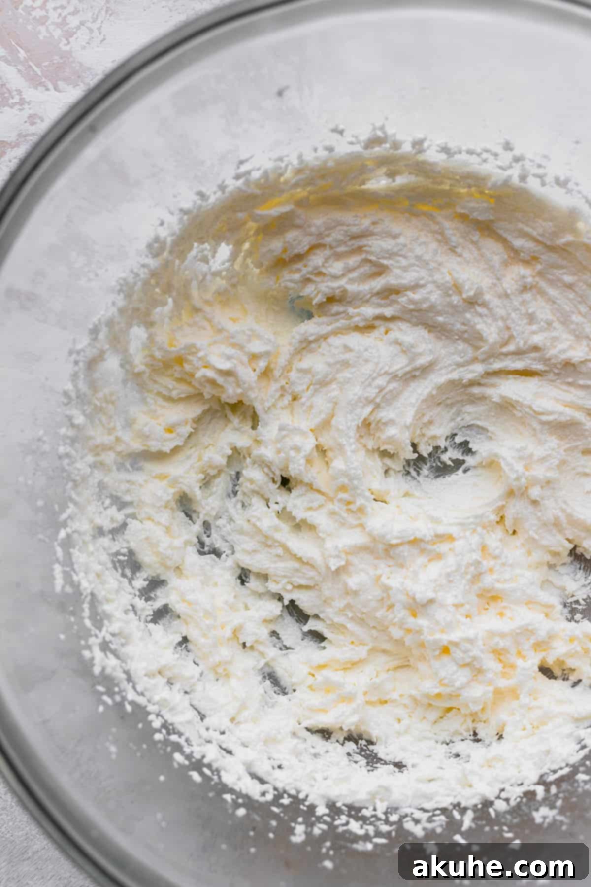 Vanilla Bean Mini Cakes 4 Close-up of butter and sugar being beaten to a light, fluffy consistency in a glass mixing bowl.
