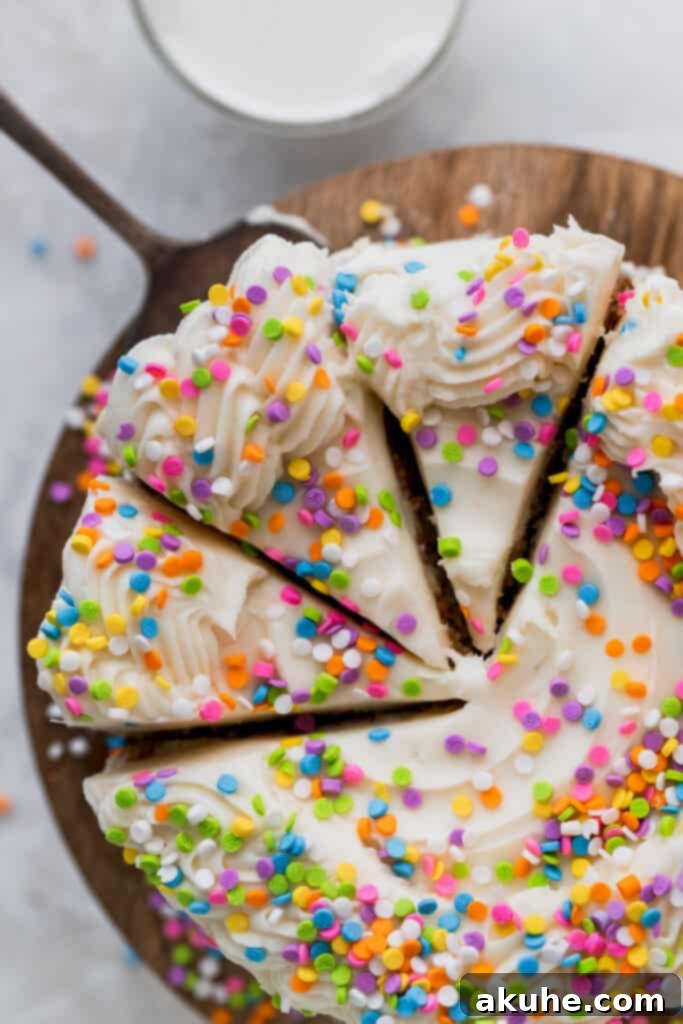 Vanilla Bean Mini Cakes 9 Top-down view of a festive mini vanilla cake with three slices cut out, revealing the soft interior and frosting layers.