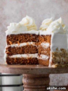 Mini carrot cake on a cake stand cut into a slice, ready to be served.
