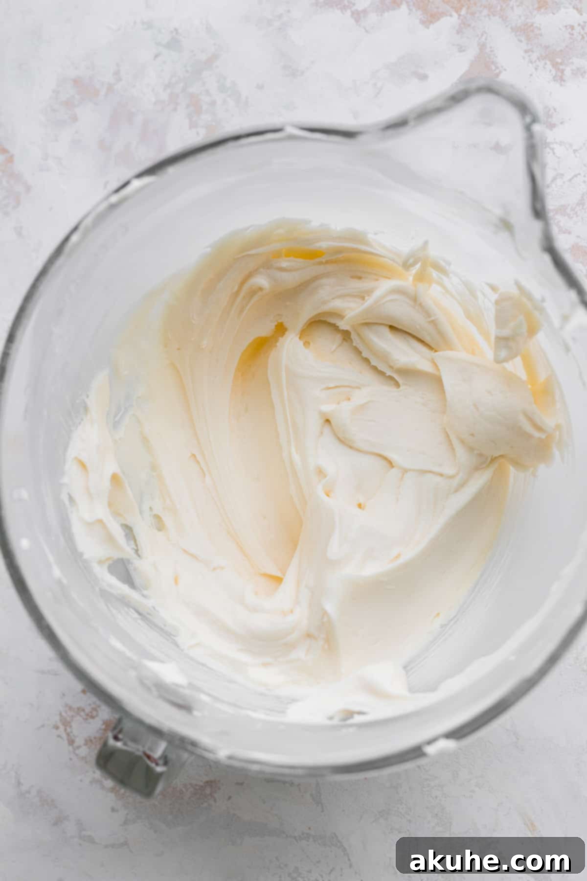 Smooth and creamy cream cheese frosting in a glass mixing bowl.