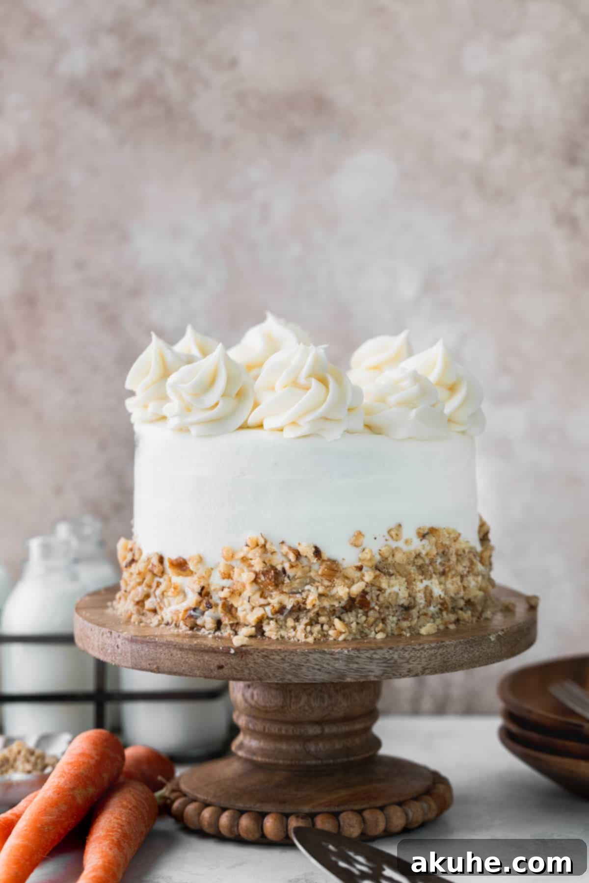 A fully frosted and decorated mini carrot cake with walnuts on a cake stand.
