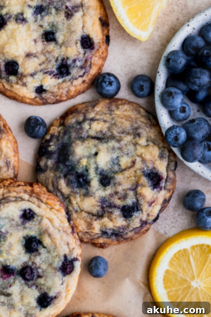 Close-up top view of freshly baked lemon blueberry cookies on a cooling rack, showcasing their golden edges and plump blueberries.