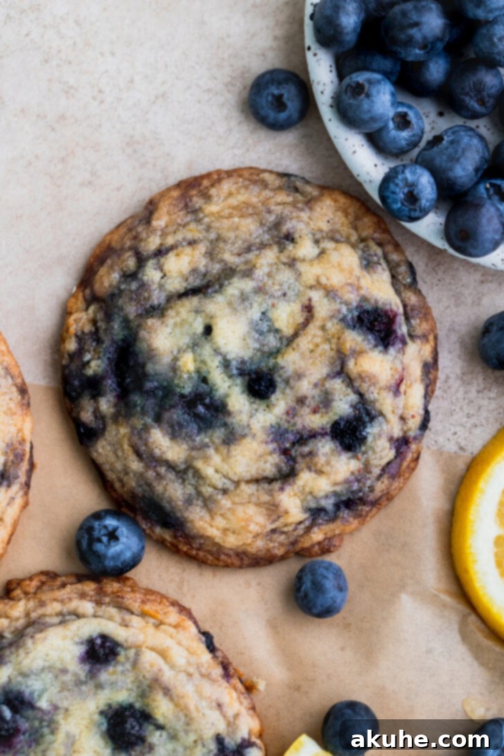 A single perfectly baked lemon blueberry cookie on a parchment-lined baking sheet, showcasing golden edges.