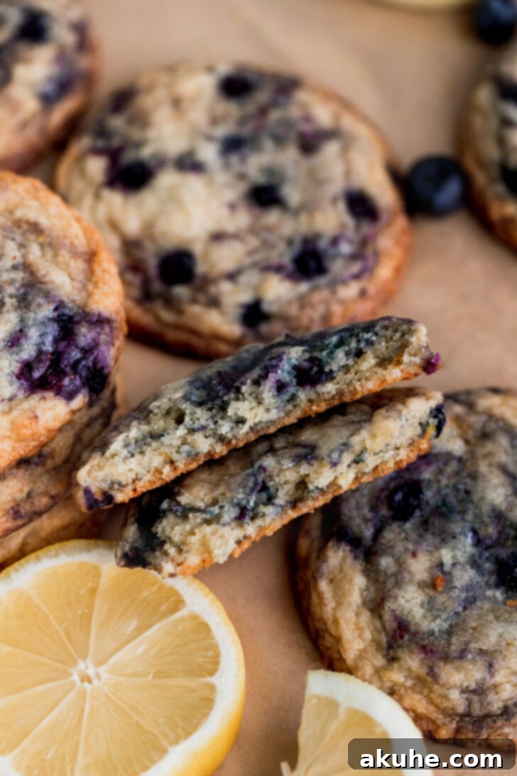 A lemon blueberry cookie split in half, revealing its chewy interior and the vibrant, juicy blueberries inside.
