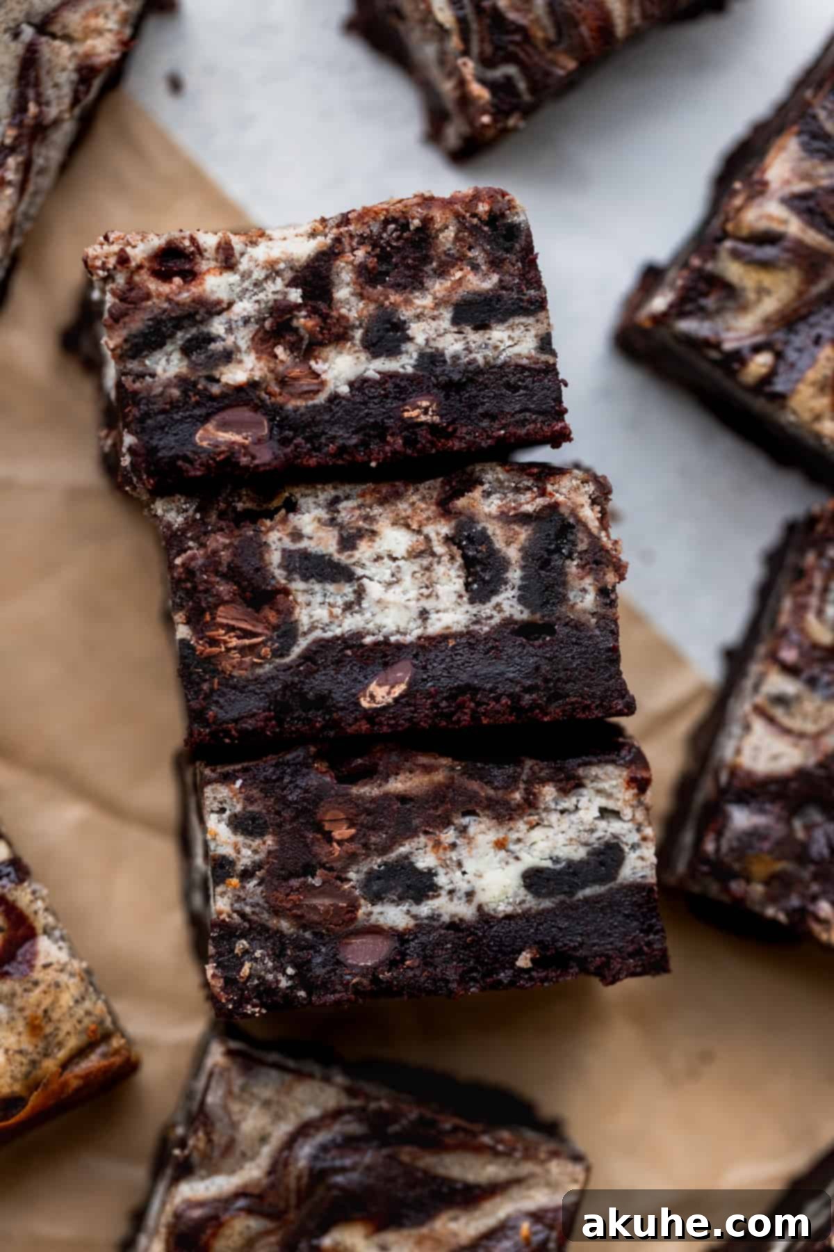Decadent Oreo Cheesecake Brownies 11 Three brownies on its side stacked together on parchment paper.