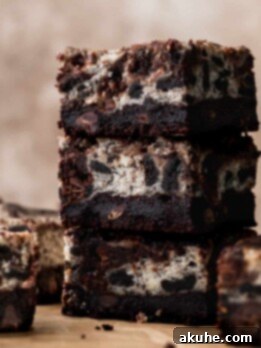 Decadent Oreo Cheesecake Brownies 13 Oreo cheesecake brownies stacked on top of each other.
