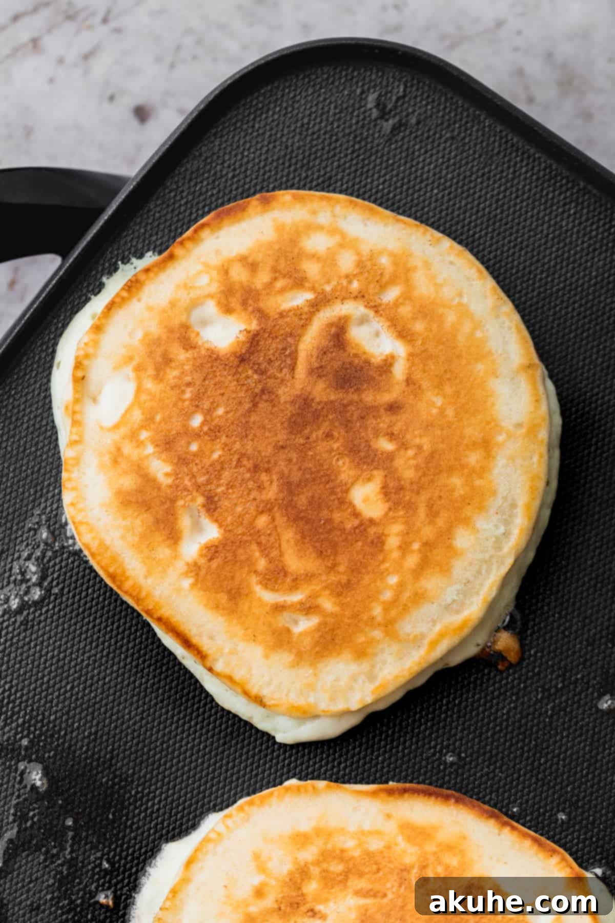 Heavenly Sweet Cream Pancakes 7 A perfectly cooked golden brown sweet cream pancake on a hot griddle, ready to be flipped or removed.