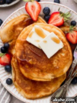 Heavenly Sweet Cream Pancakes 10 Close up of sweet cream pancakes on a large plate with strawberries and blueberries.