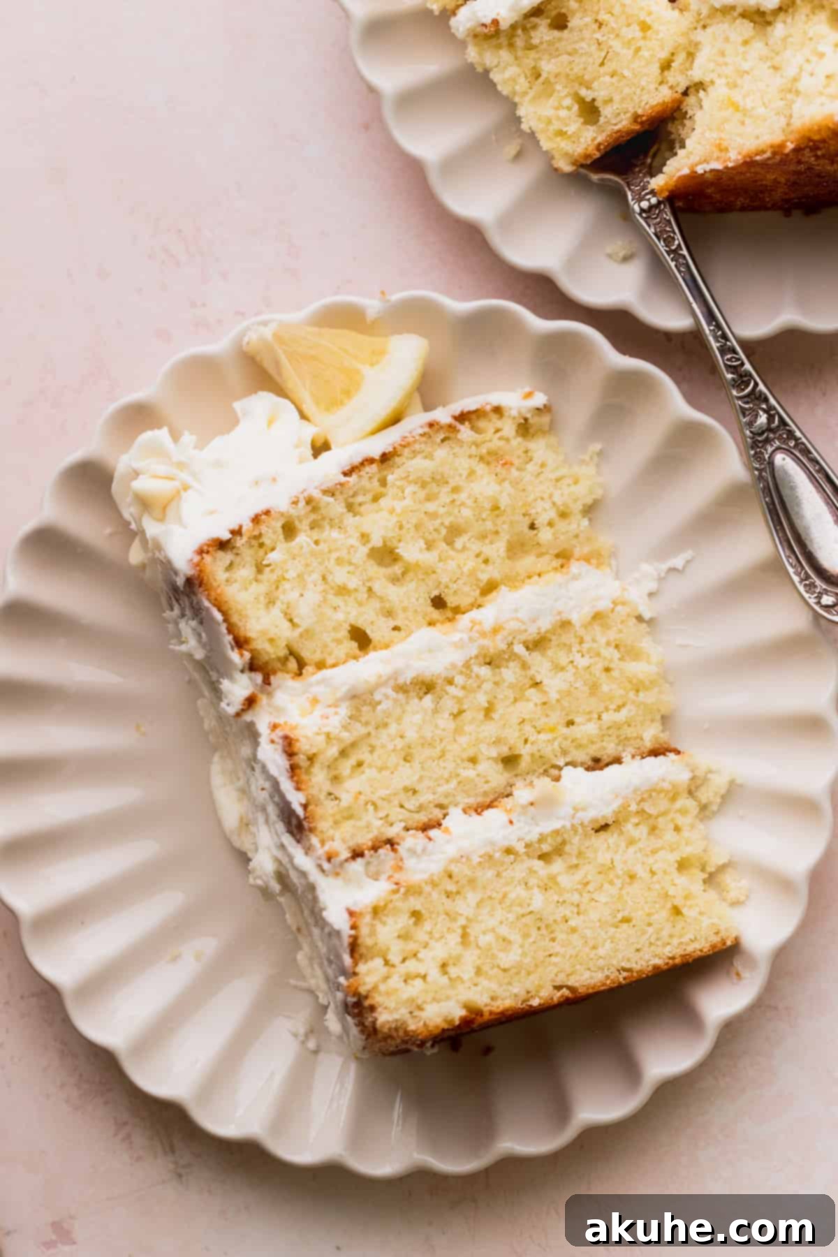 Decadent Lemon White Chocolate Bliss 2 A close-up shot of a single slice of Lemon White Chocolate Cake, showcasing its distinct layers and creamy frosting, elegantly presented on a plate.