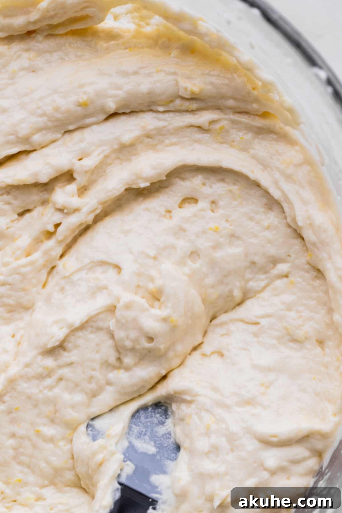 Decadent Lemon White Chocolate Bliss 6 A close-up of light and fluffy lemon cake batter in a mixing bowl, ready to be poured into cake pans.
