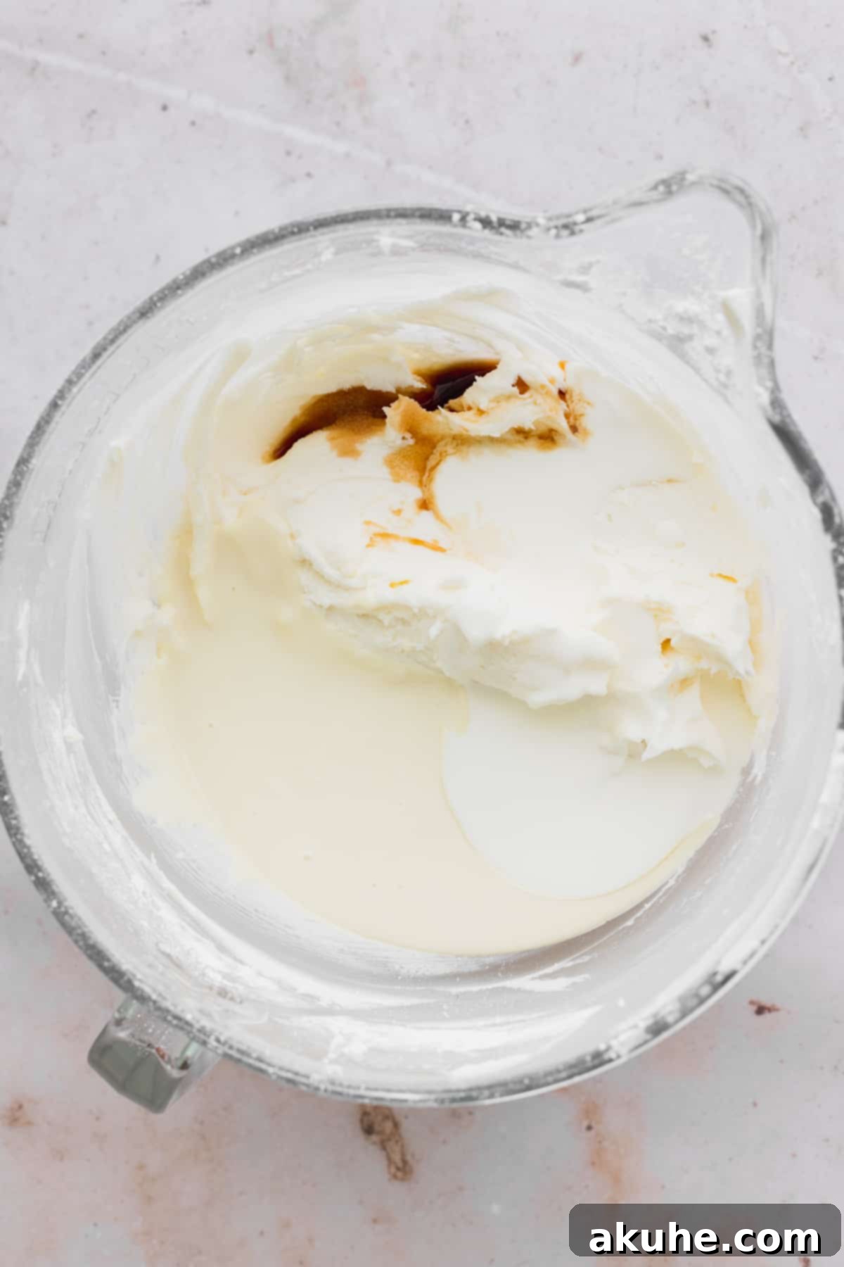 Decadent Lemon White Chocolate Bliss 8 Melted white chocolate drizzled over creamy frosting in a glass bowl, showcasing its smooth texture.