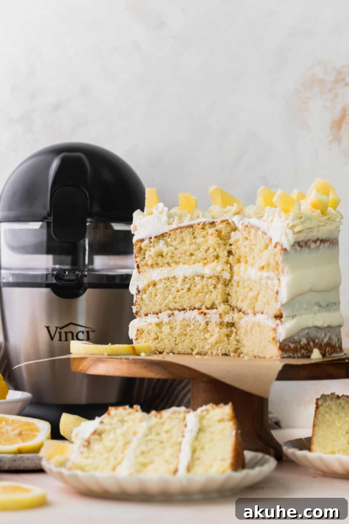 Decadent Lemon White Chocolate Bliss 10 A beautifully assembled Lemon White Chocolate Cake on a wooden cake stand, revealing its moist layers and creamy frosting in a cross-section.