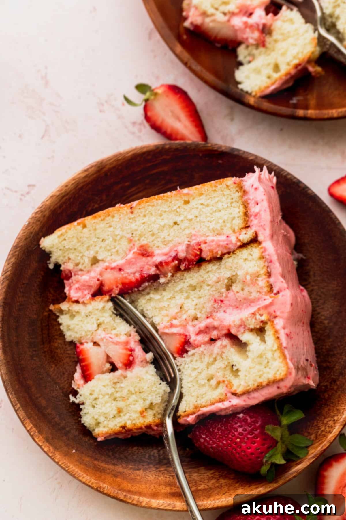 Sweet Strawberry Vanilla Dream 13 One slice of strawberry vanilla cake on a plate with a fork inserted, ready to be enjoyed.
