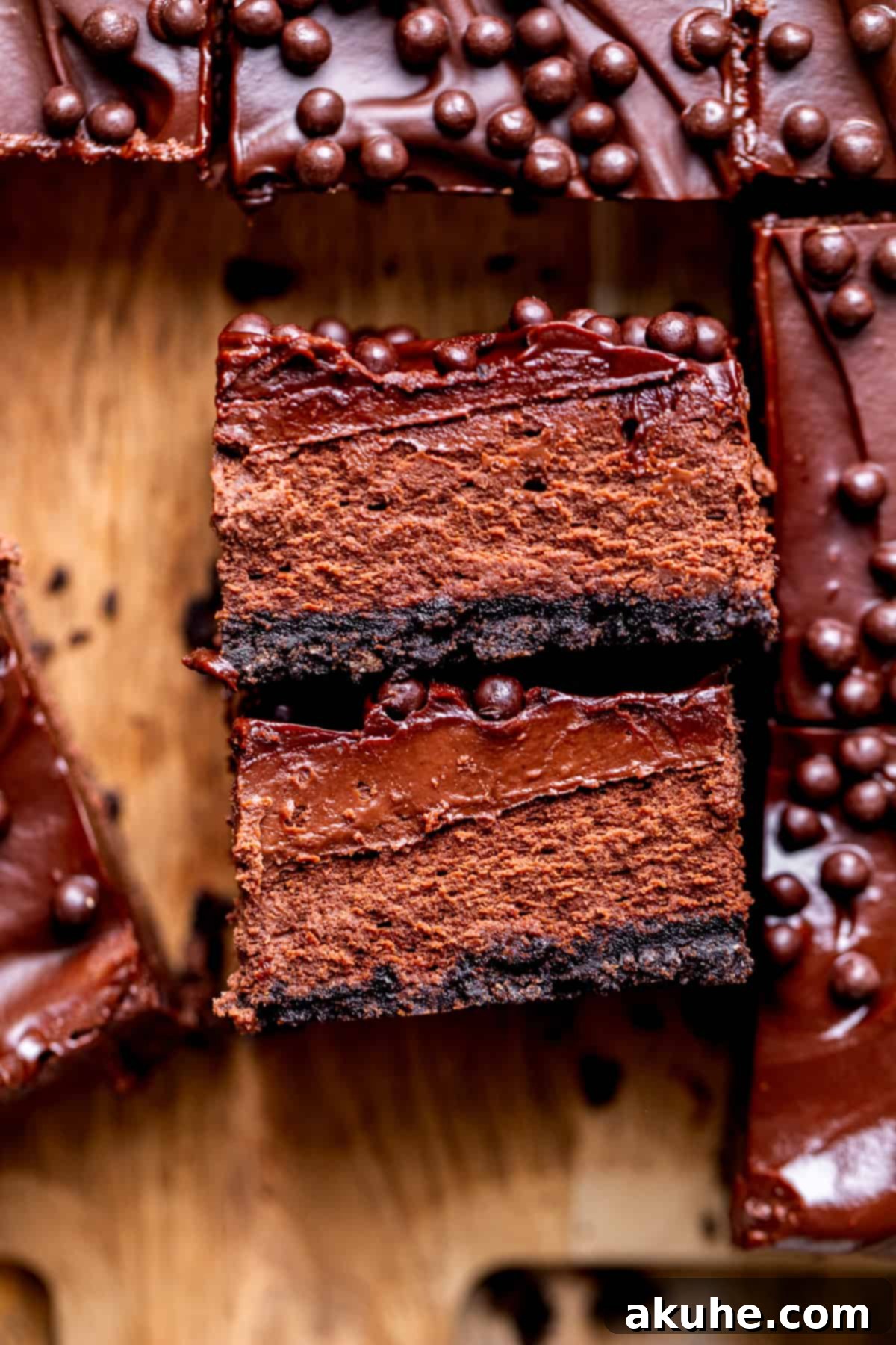 Decadent Chocolate Cheesecake Squares 3 Two chocolate cheesecake bars, elegantly presented on their side, highlighting the distinct layers and the glossy chocolate ganache.