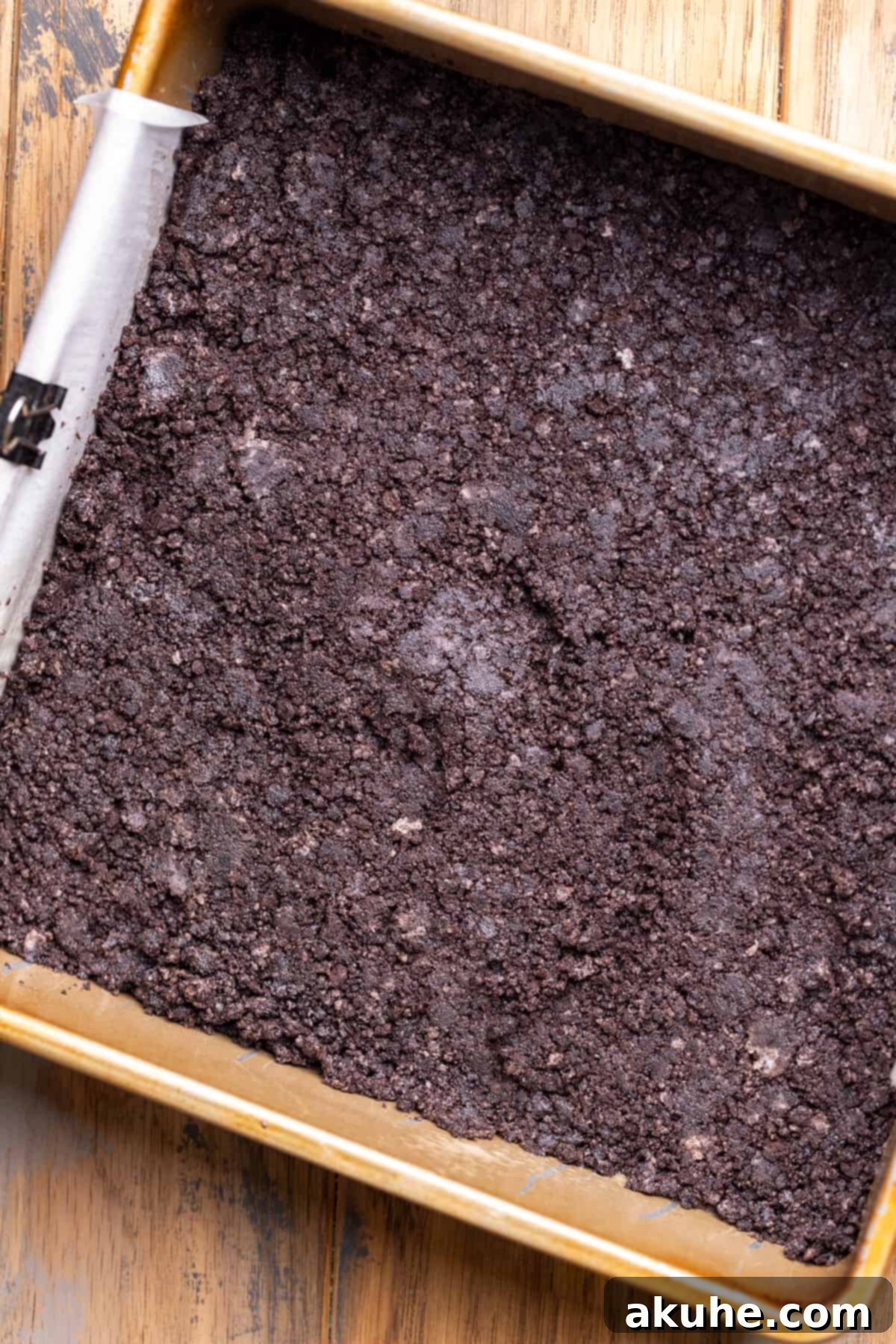 Decadent Chocolate Cheesecake Squares 4 Oreo crust perfectly pressed into the bottom of a square baking pan, ready for the cheesecake batter.