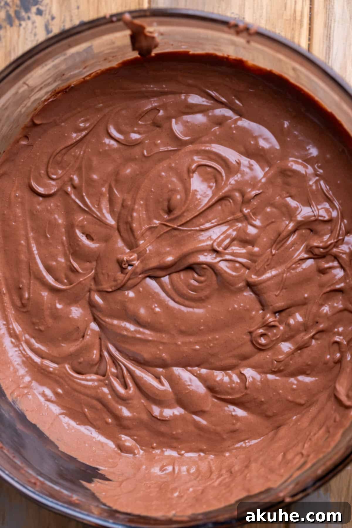 Decadent Chocolate Cheesecake Squares 5 Creamy chocolate cheesecake batter, rich and smooth, in a clear glass mixing bowl, ready to be poured.