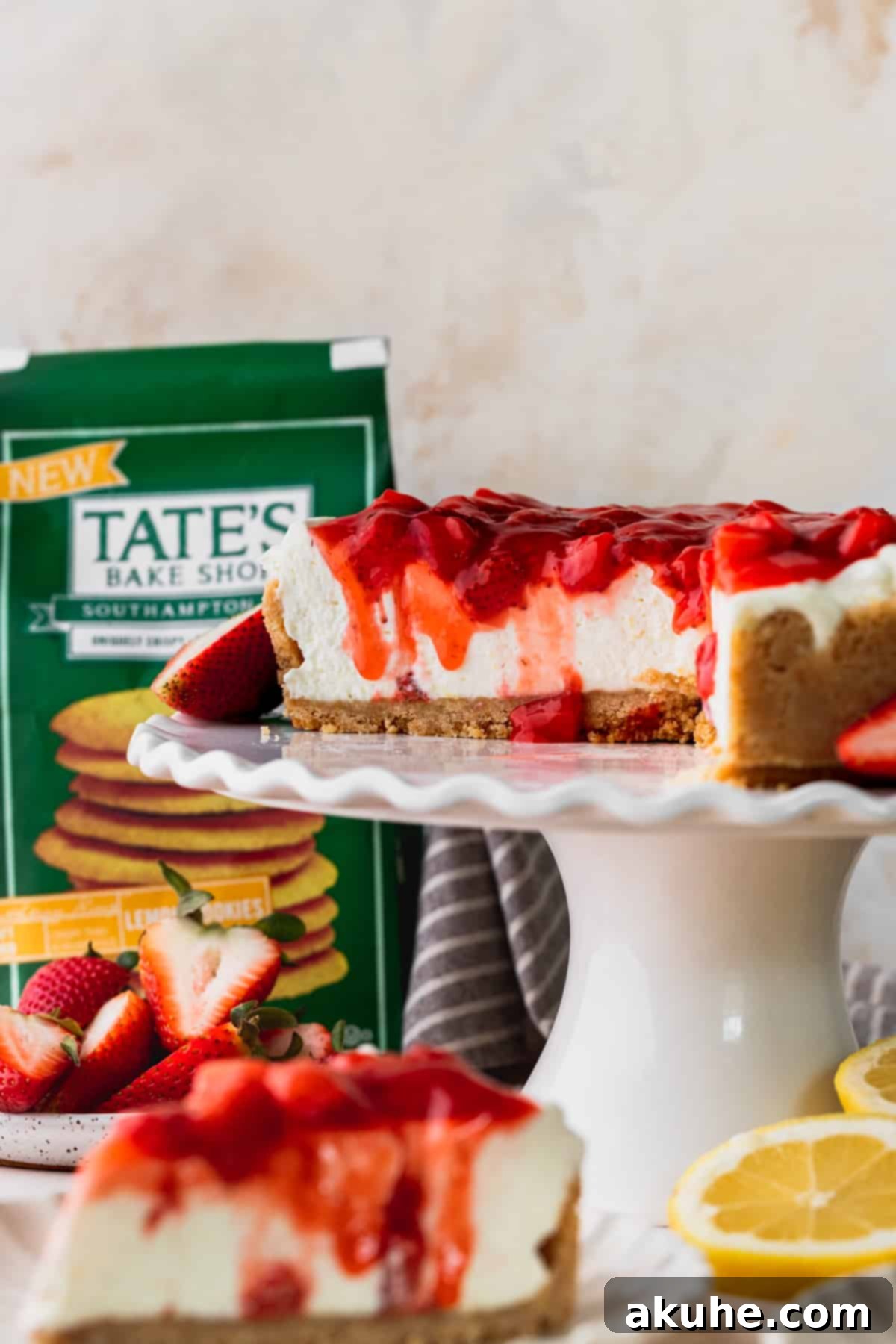 Lemon cheesecake with strawberry sauce cut into on a cake stand.