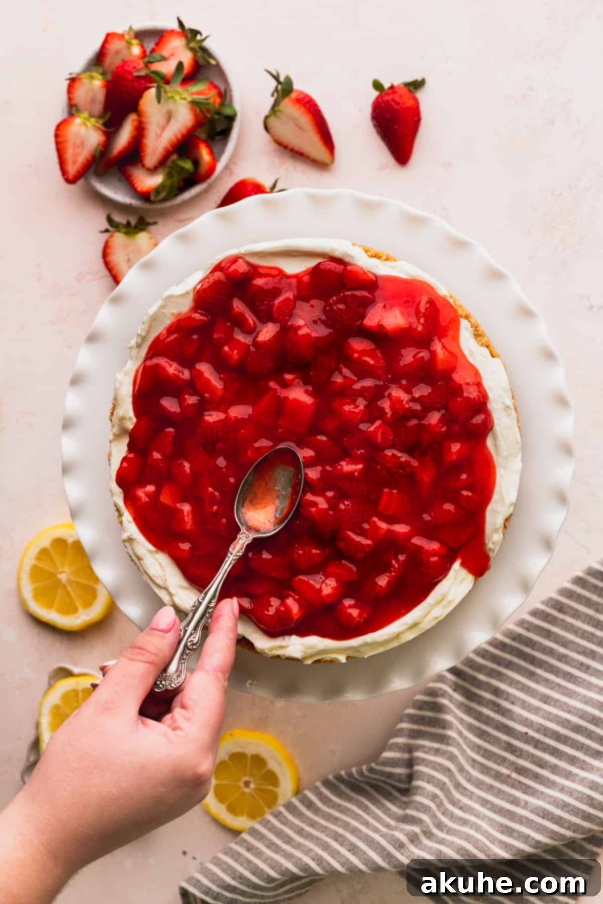 Spreading strawberry sauce over the cheesecake.