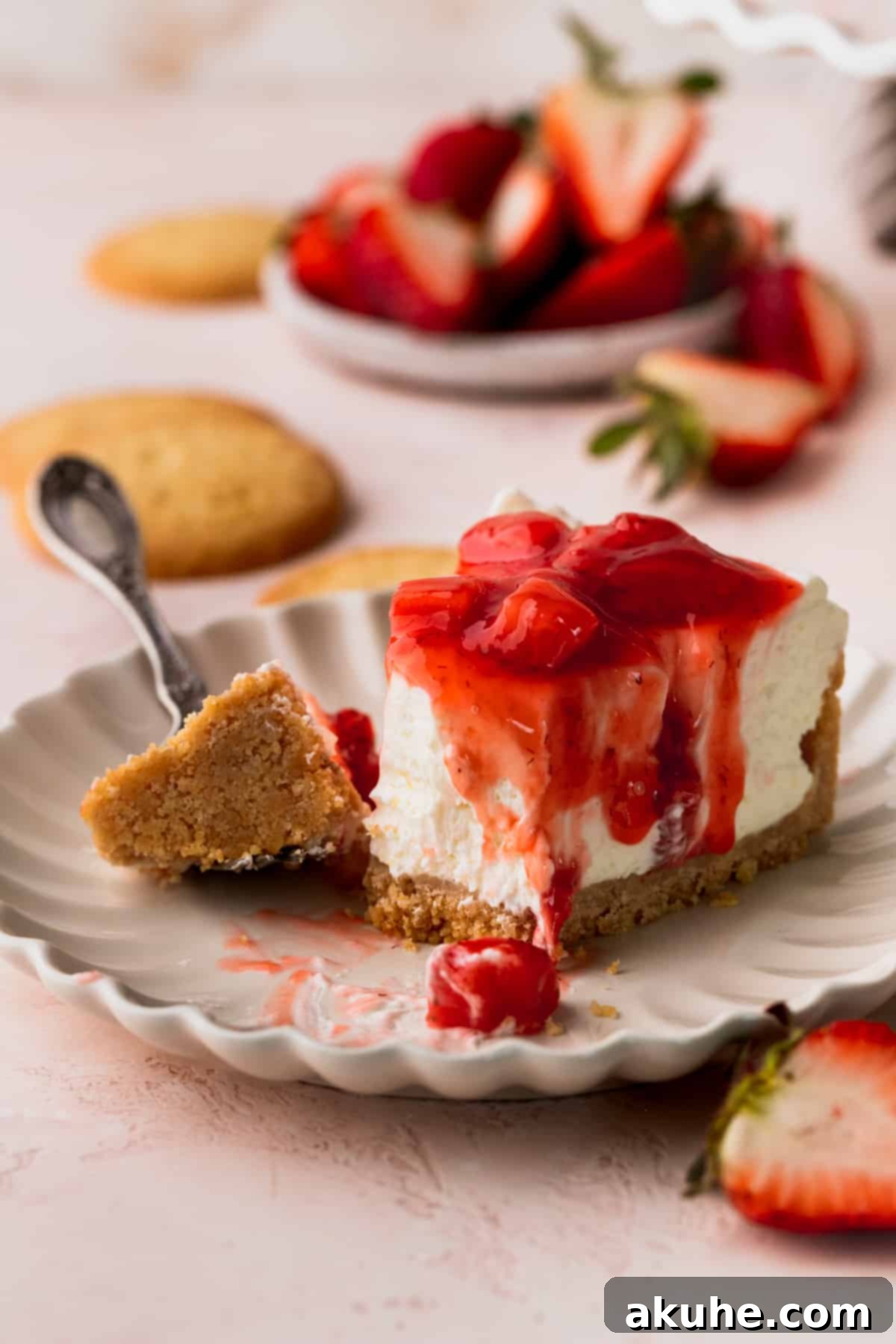 One slice of cheesecake with a bite missing on a plate.