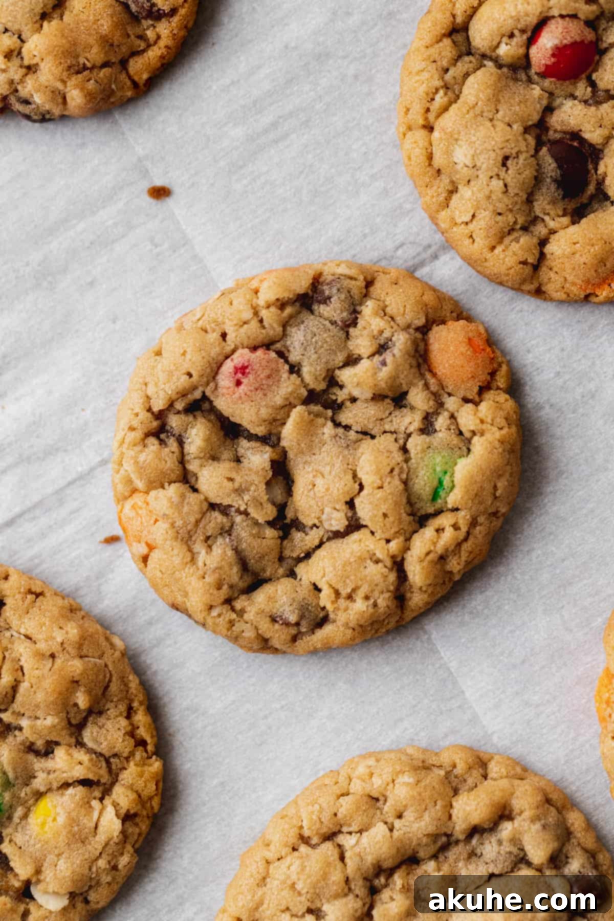 Small, perfectly baked monster cookies on parchment paper, ready to be used as delightful decorations for the cheesecake.