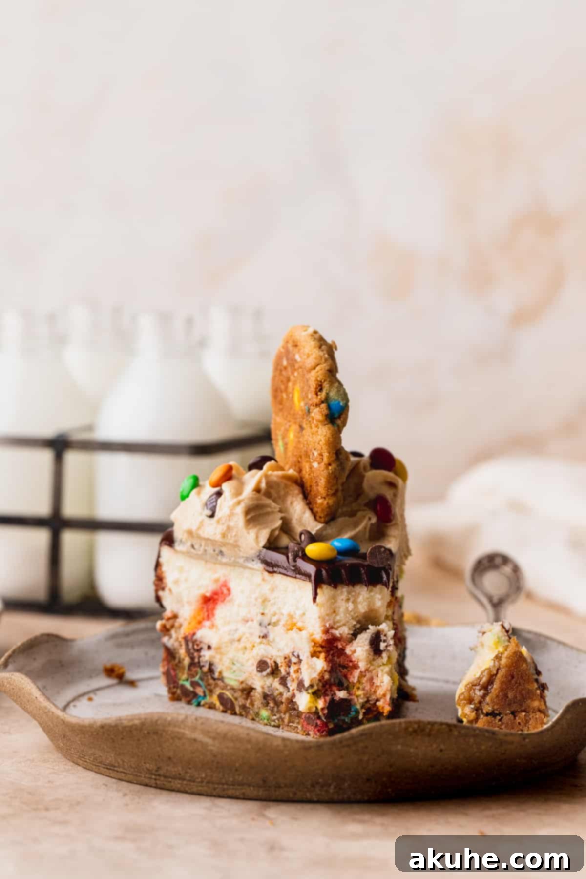 A close-up of a delightful slice of Monster Cookie Cheesecake on a plate, with a small bite taken, highlighting its tempting layers and textures.