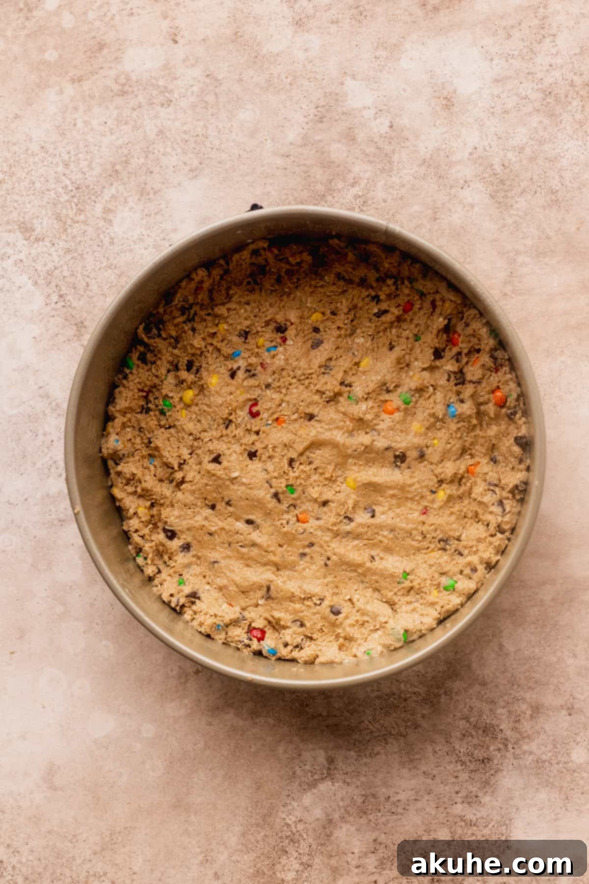 The monster cookie dough perfectly pressed into the bottom of a 9-inch springform pan, ready for baking.