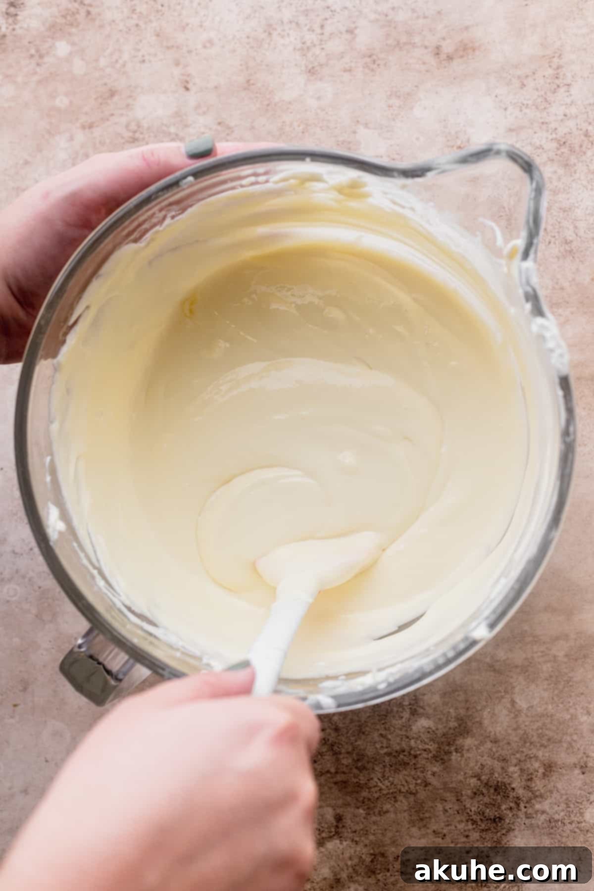 Smooth, creamy cheesecake batter being mixed in a glass bowl, ready for its delicious additions.