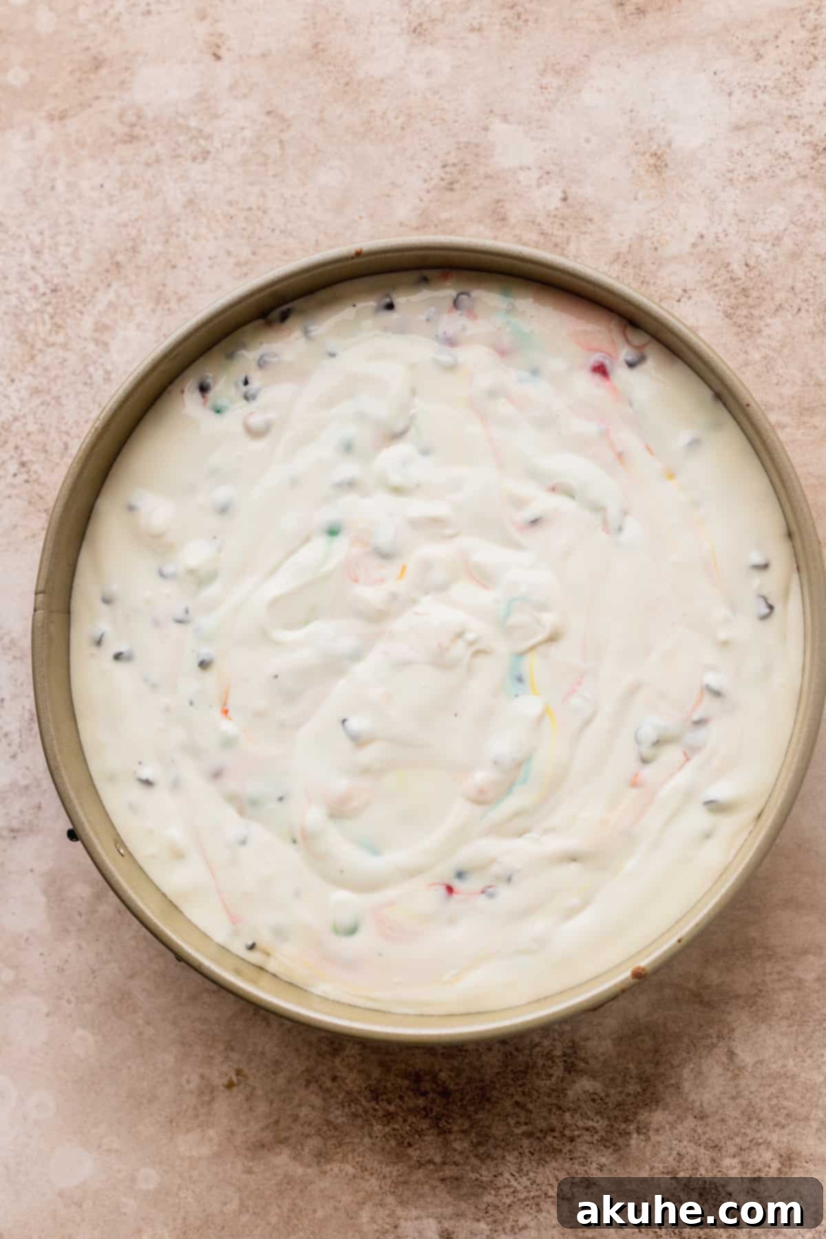 Smooth cheesecake batter poured over the monster cookie crust in a springform pan, ready for its water bath.
