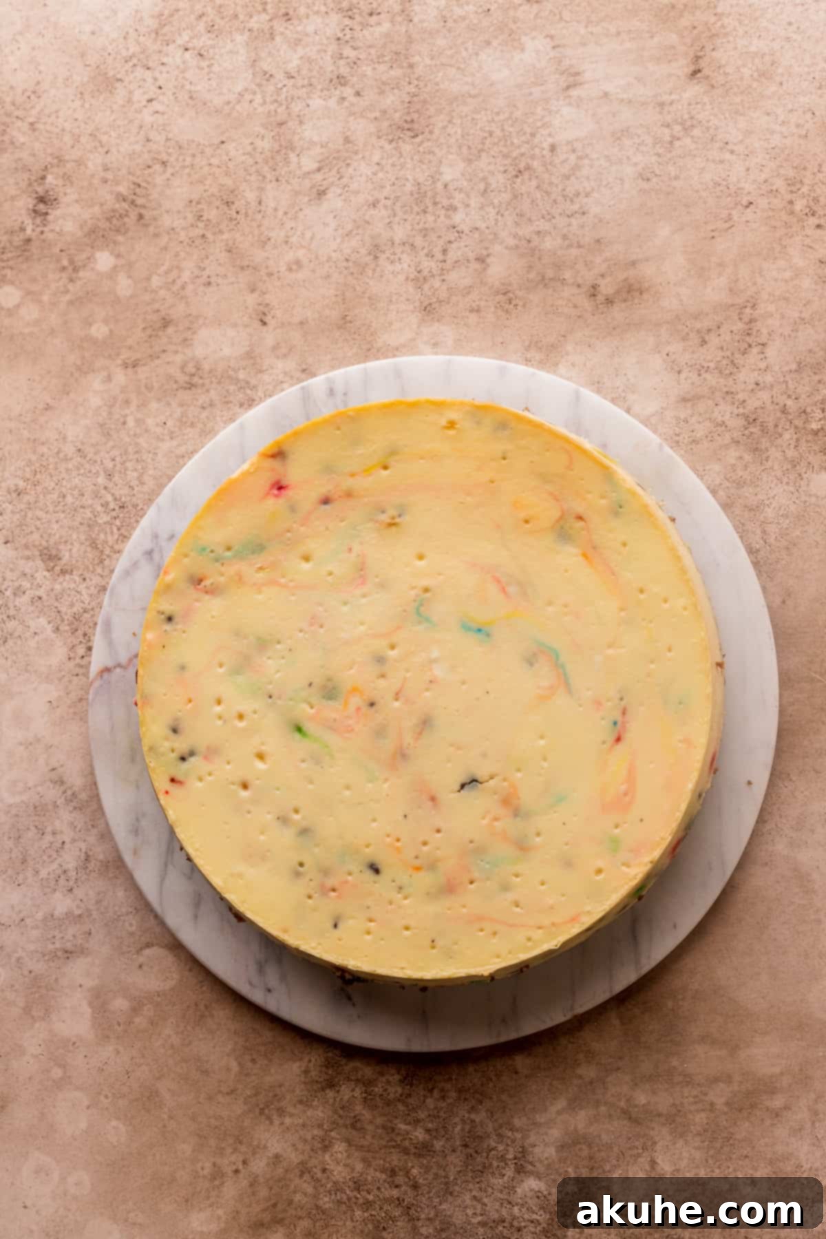 A perfectly baked and chilled cheesecake, removed from its pan and placed on a platter, showcasing its smooth top and ready for decoration.