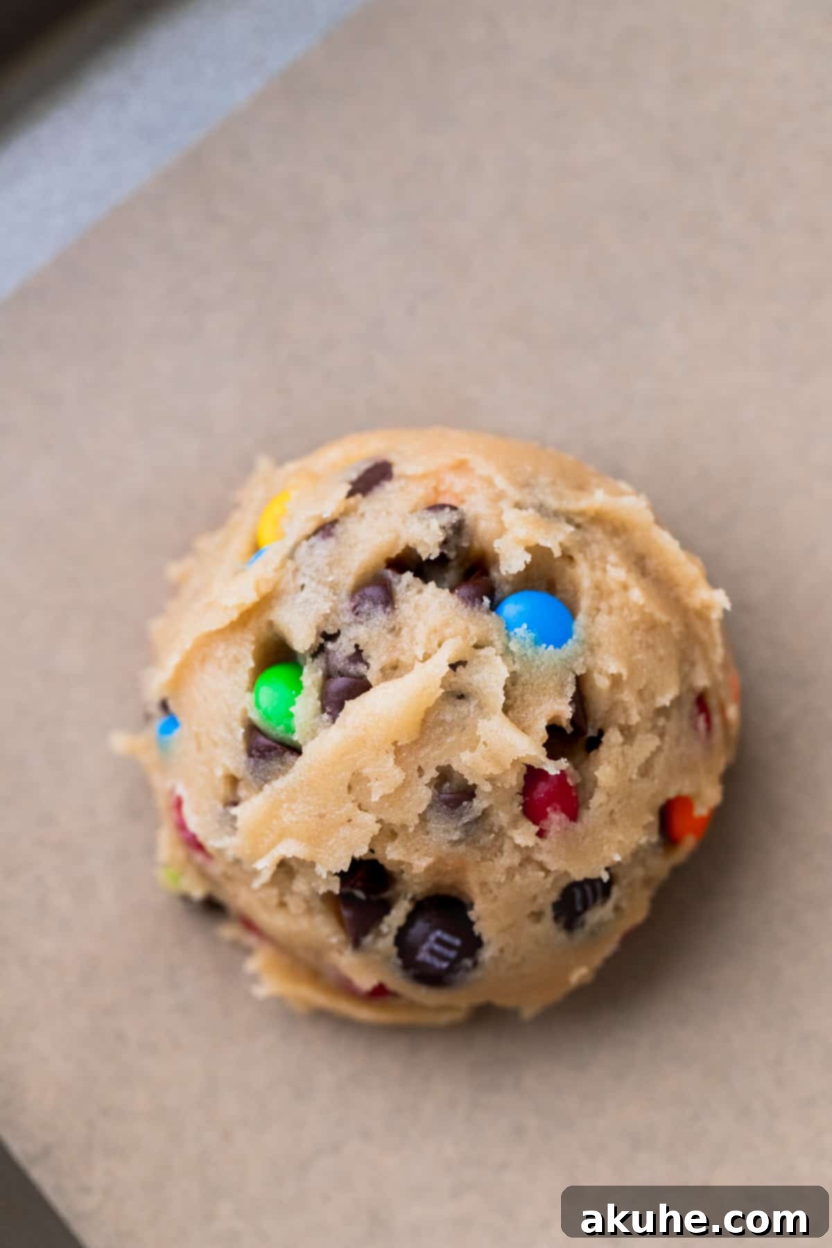 A perfectly portioned cookie dough ball resting on parchment paper, ready for chilling.