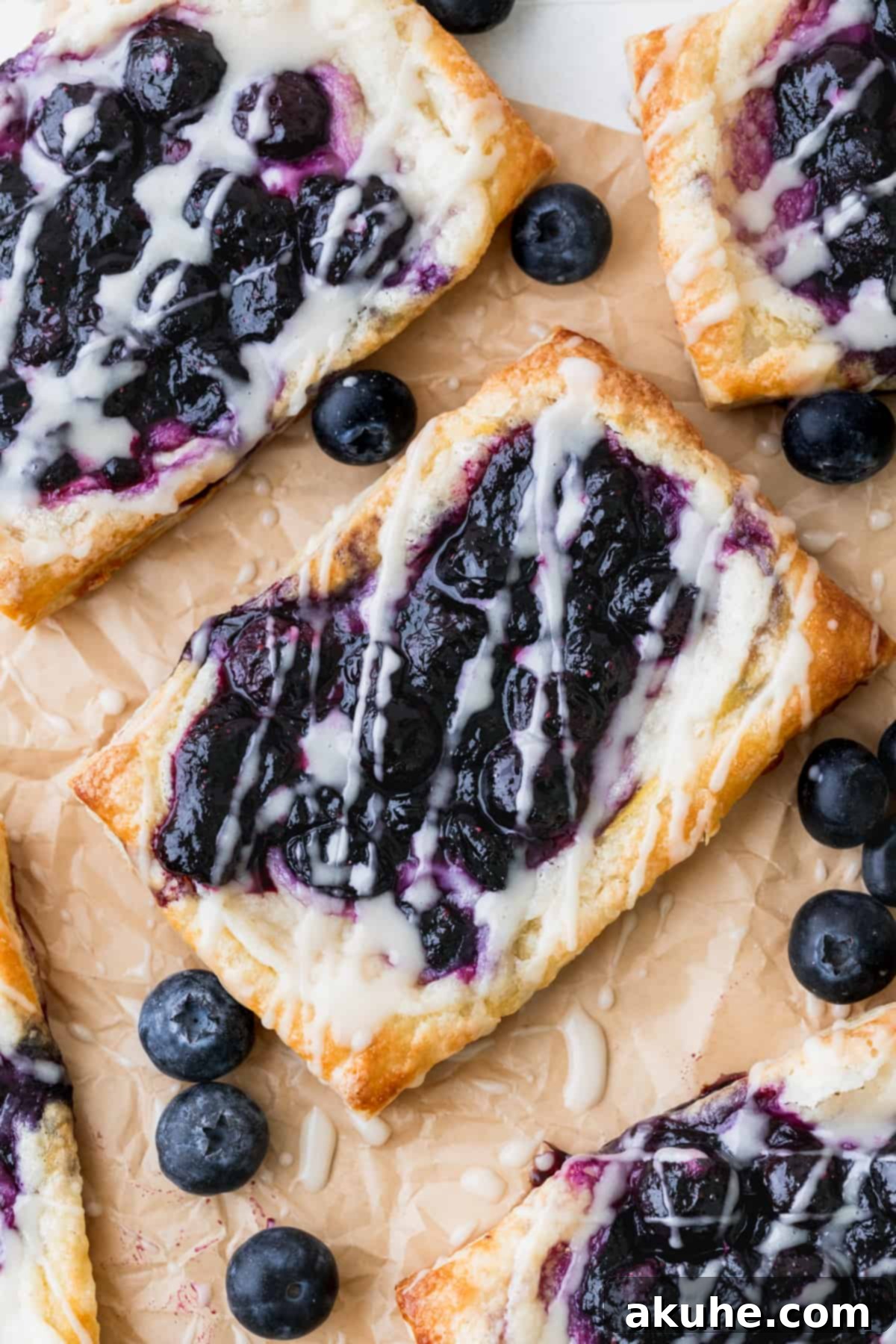 Blueberry danishes neatly arranged on parchment paper, showcasing their golden edges and delicious fillings.