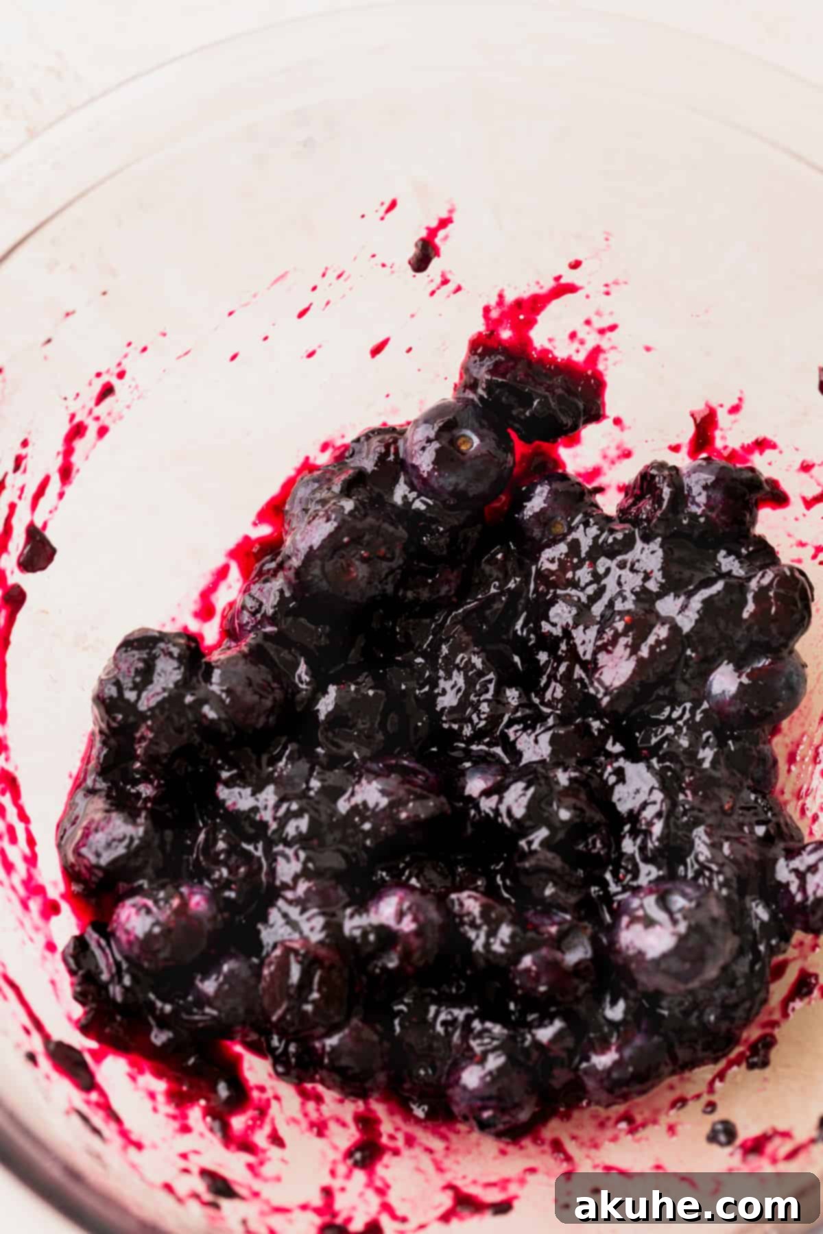 Blueberry preserves cooling in a glass bowl.