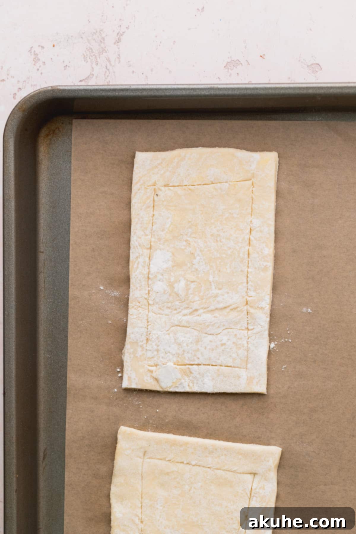 Puff pastry sheet with scored rectangles on a cookie sheet.