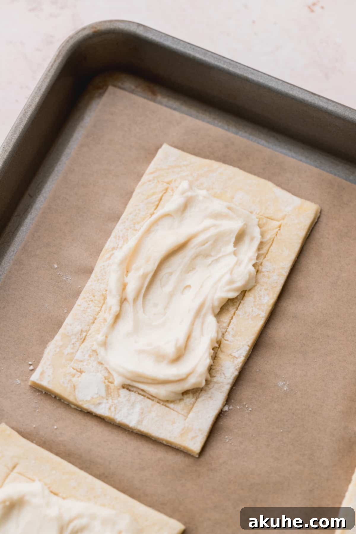 Cream cheese filling spread on one pastry rectangle.