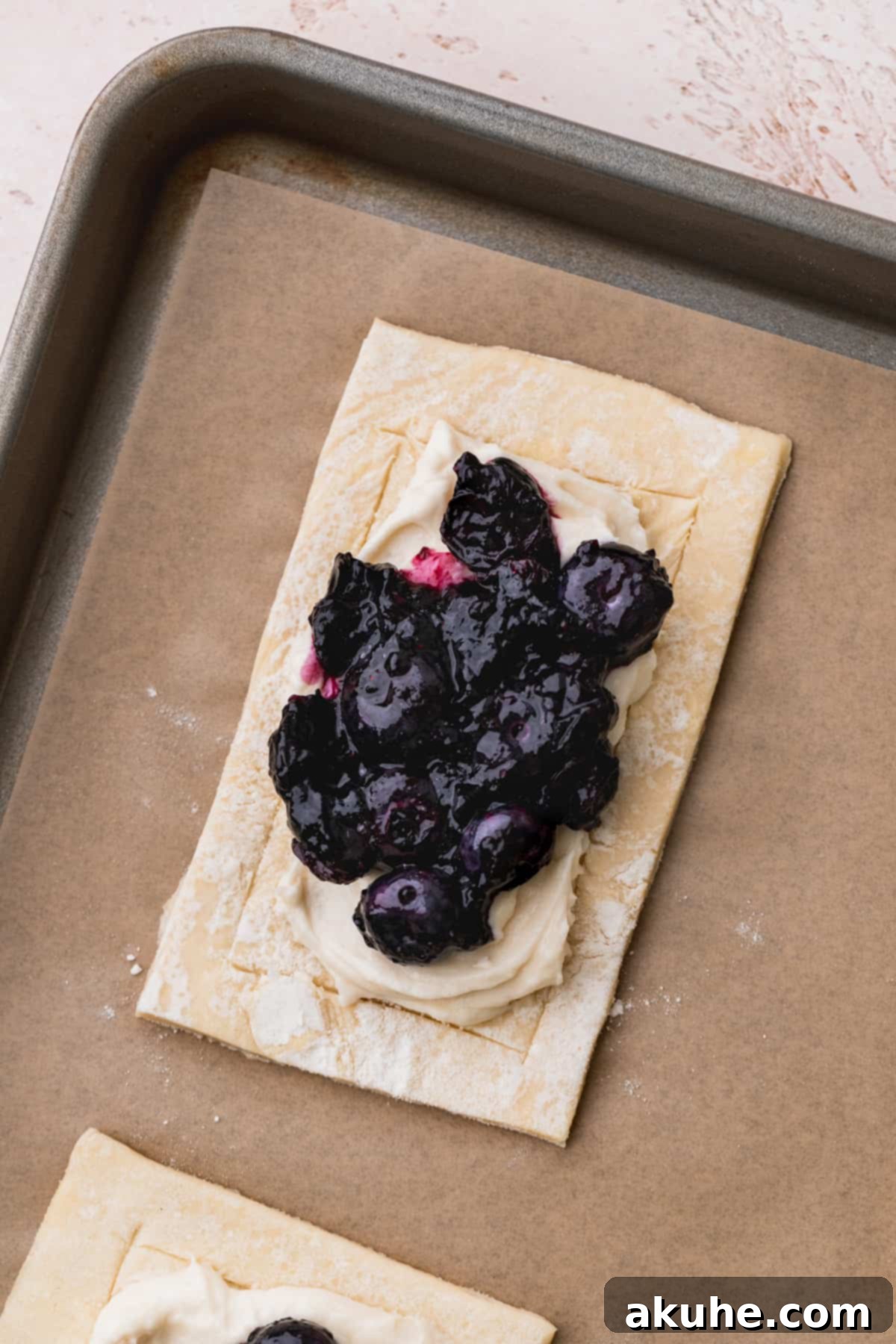 Blueberry preserves on top of cream cheese filling on pastry rectangle.