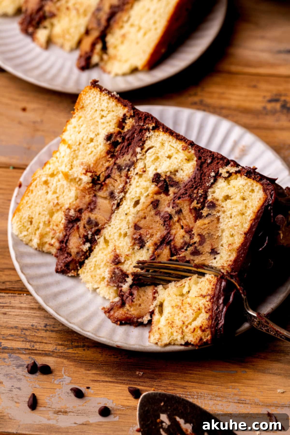 Decadent Cookie Dough Cake 14 A fork inserted into a slice of Cookie Dough Dream Cake on a white plate, ready to be enjoyed.
