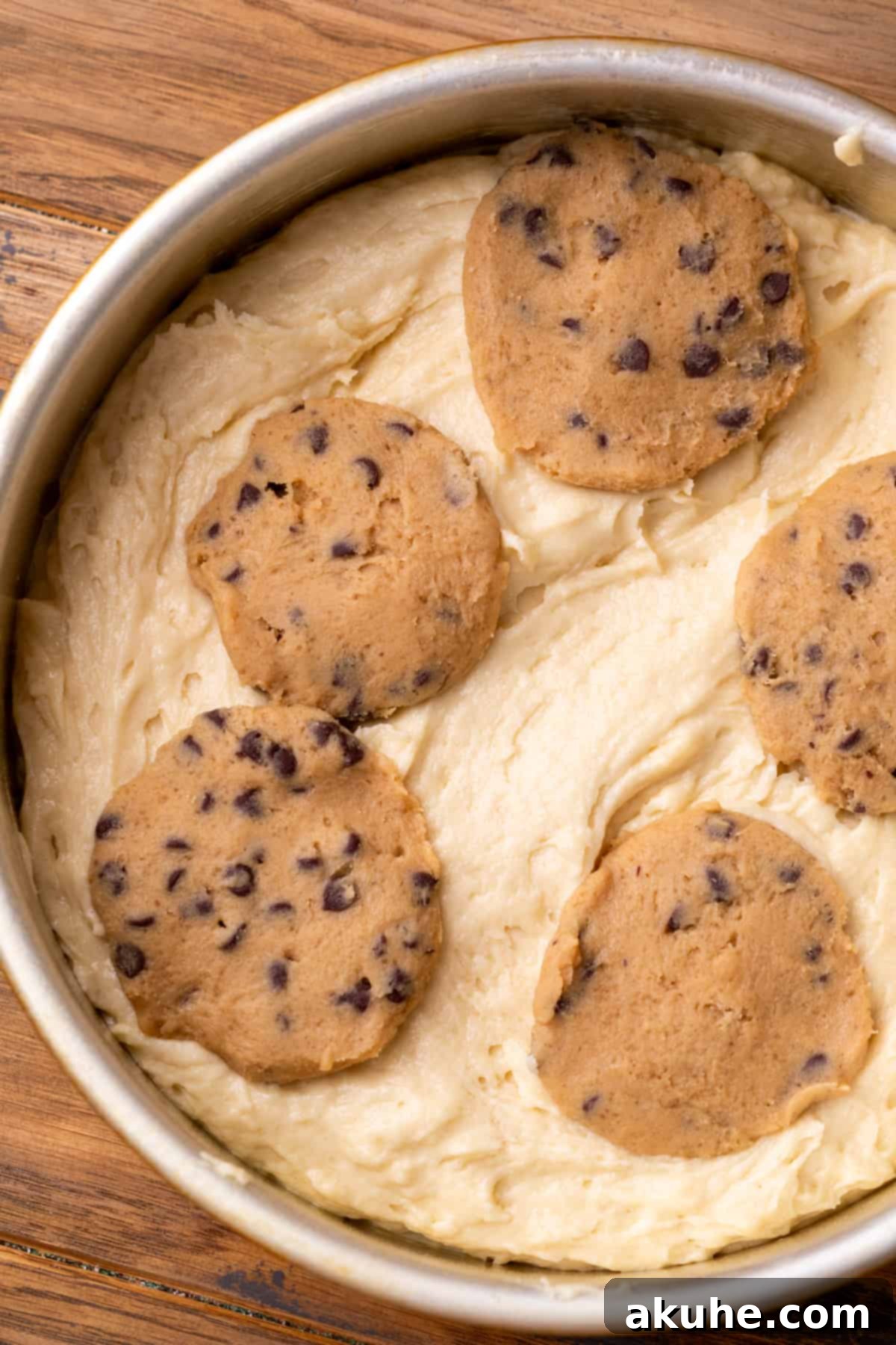 Decadent Cookie Dough Cake 8 Vanilla cake batter with edible cookie dough discs placed on top in a round baking pan, ready for the oven.