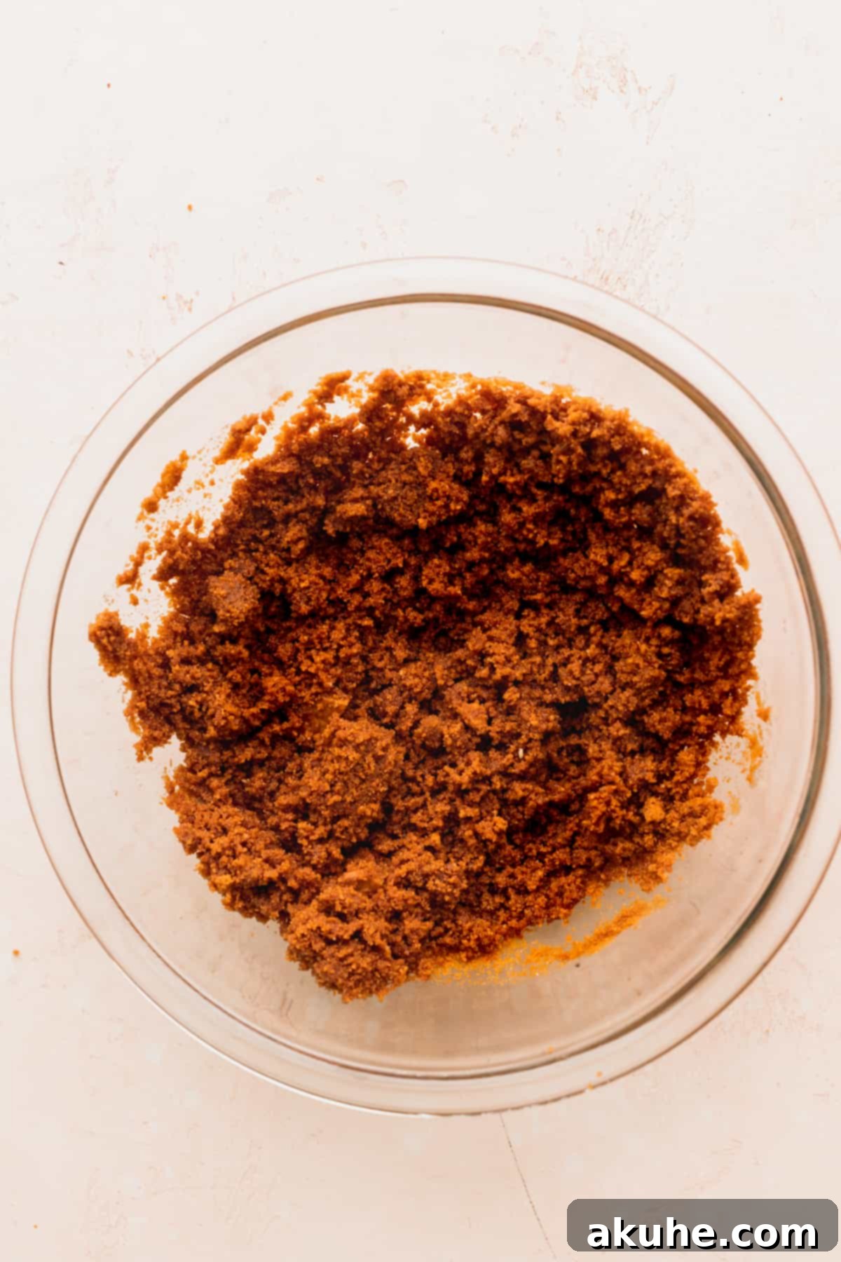 The Ultimate Biscoff Cheesecake 4 Close-up of fine Biscoff cookie crumbs in a clear glass bowl, ready for the crust.