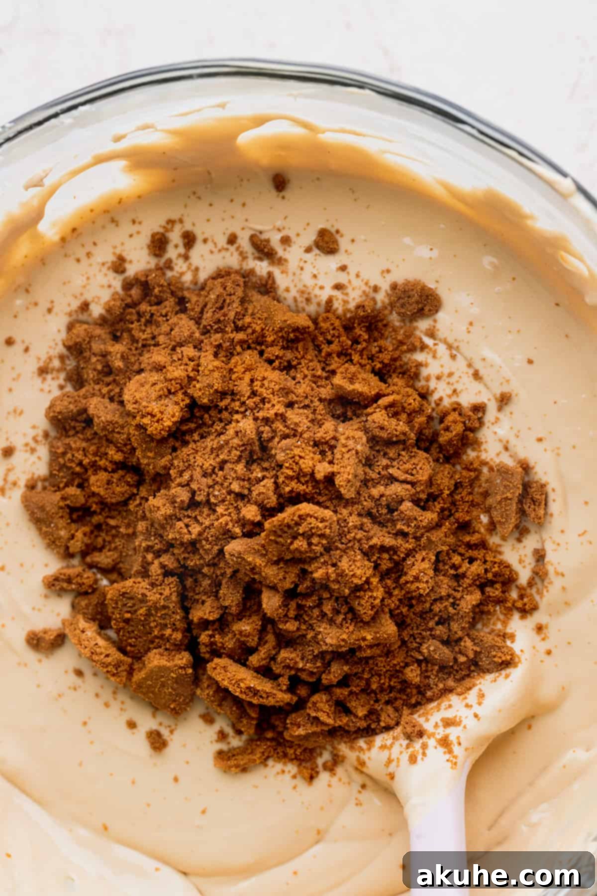 The Ultimate Biscoff Cheesecake 7 Chopped Biscoff cookie pieces sprinkled over the smooth cheesecake batter, ready to be folded in.