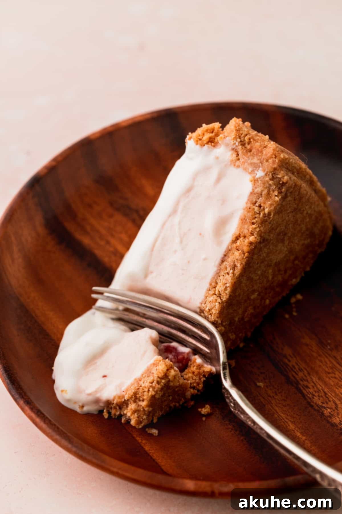 Close up view of a perfect slice of strawberry ice cream cheesecake, showcasing its layers and creamy texture.