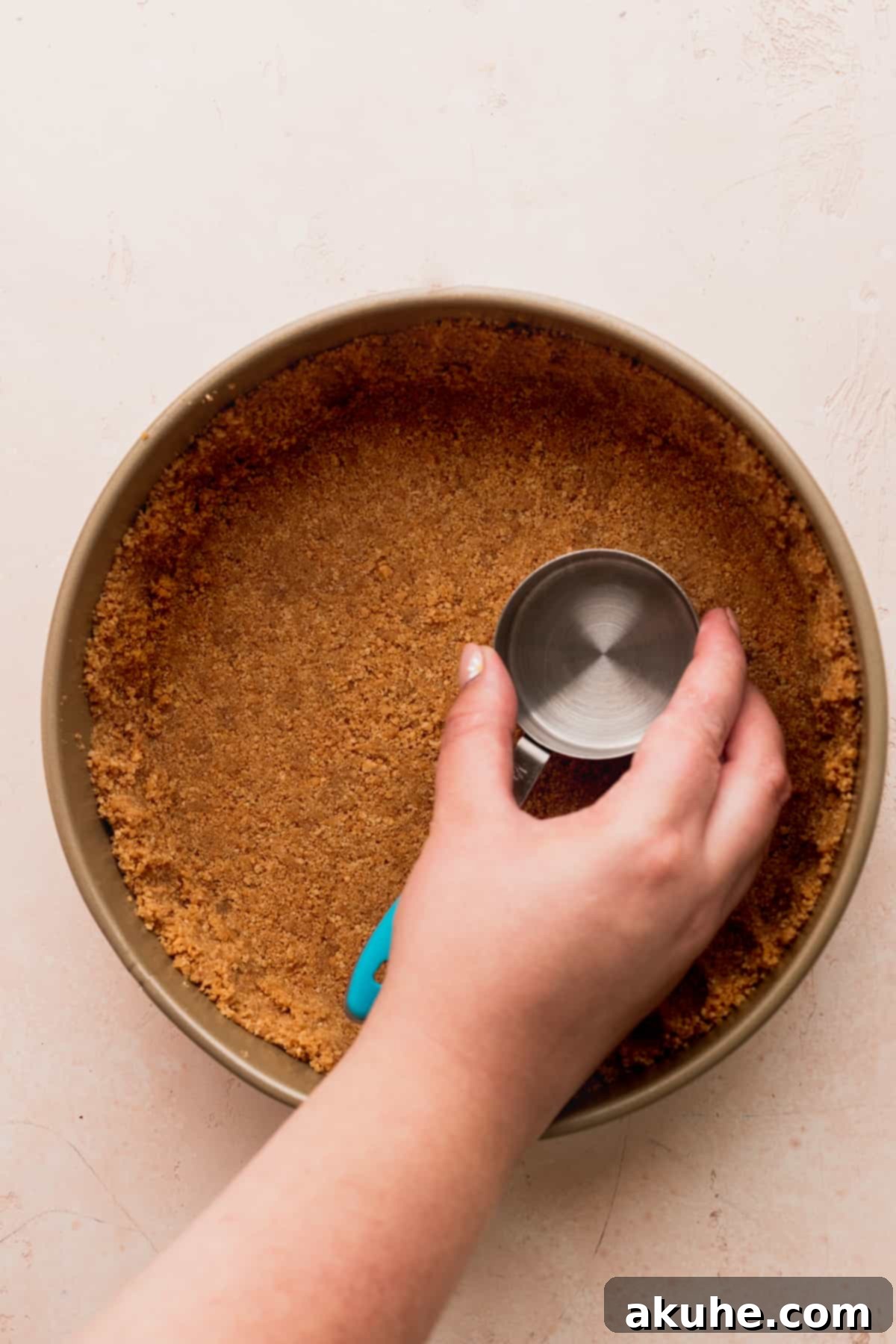 Pressed graham cracker crust lining the bottom and sides of a springform pan.