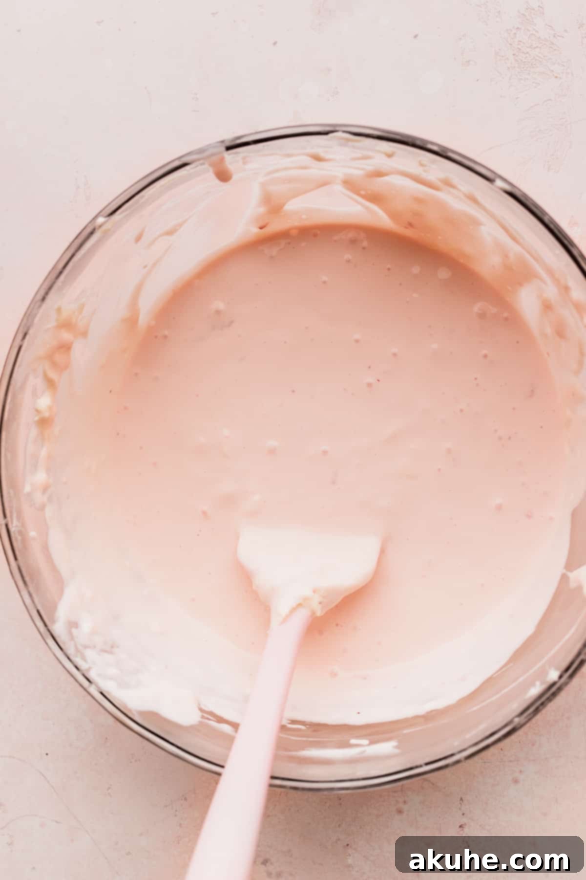 Strawberry ice cream cheesecake batter in a glass bowl after folding, showing its smooth consistency.