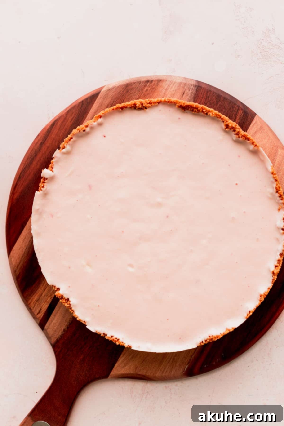 A fully set, frozen cheesecake on a wooden board, removed from the pan.