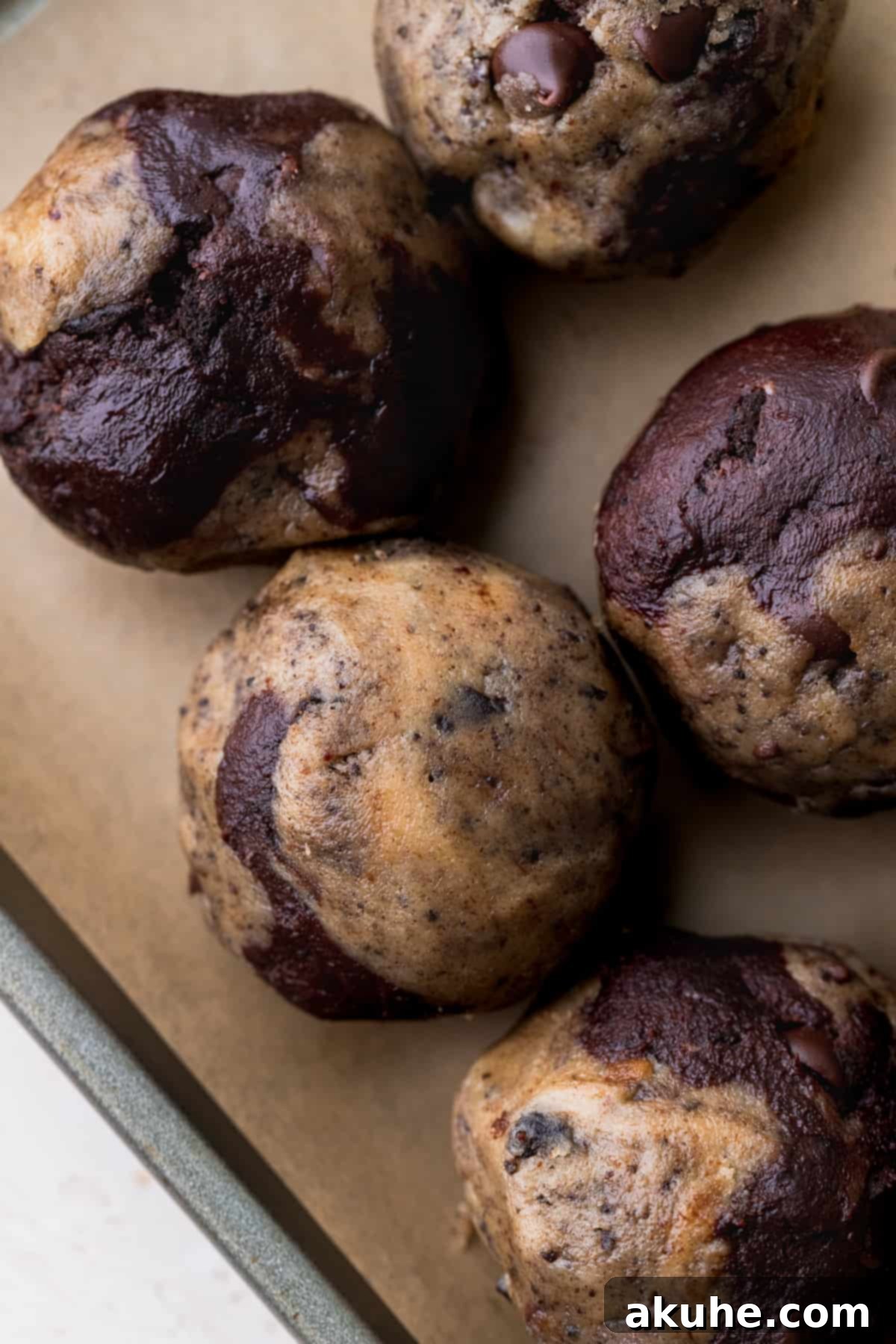 Ultimate Oreo Brookie Indulgence 11 Swirled cookie dough balls neatly arranged on a parchment-lined cookie sheet, ready for baking.